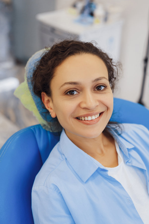 Positive female patient visiting dentist and smiling at camera in modern clinic