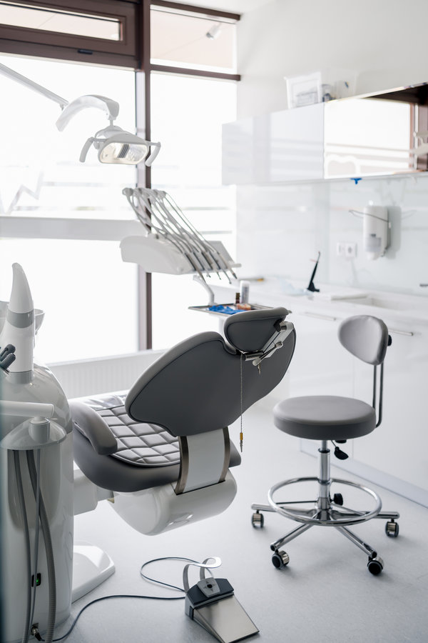Interior of dental practice room with chair, lamp, display and stomatological tools