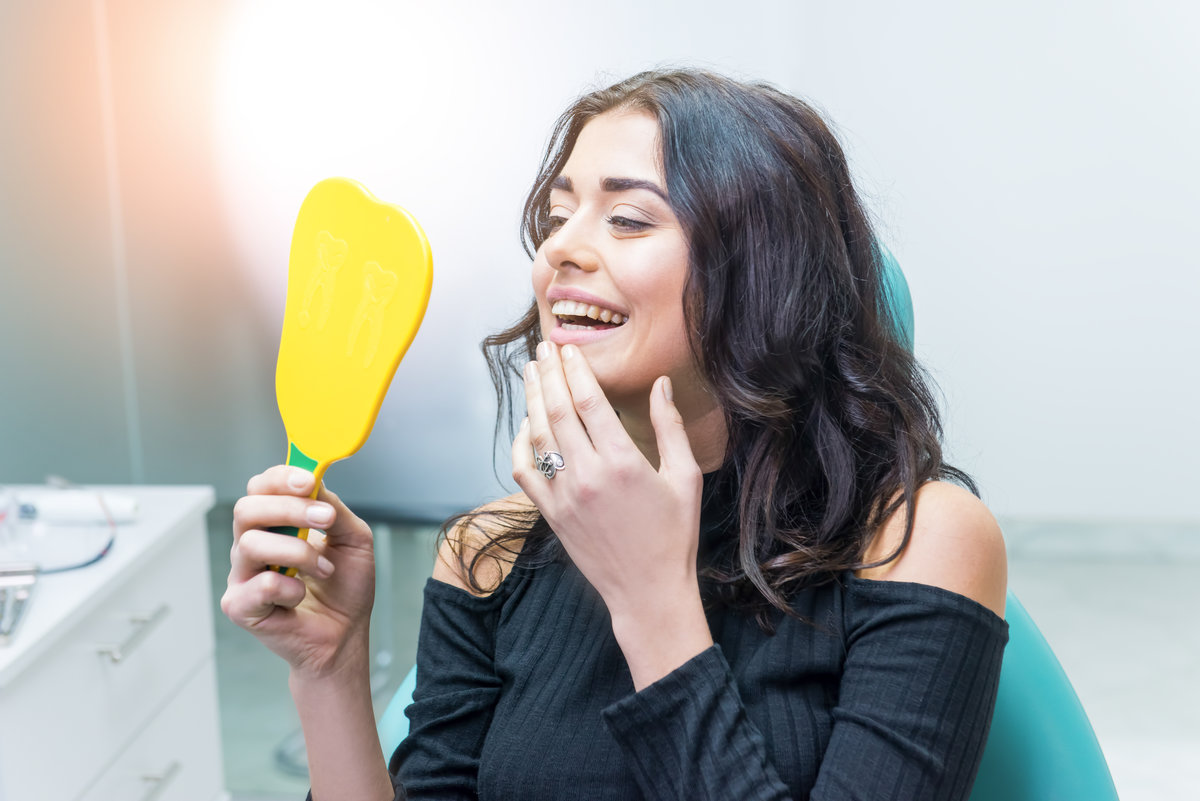 Woman looking at her teeth. Smiling lady at dentist office. Smile as a masterpiece.