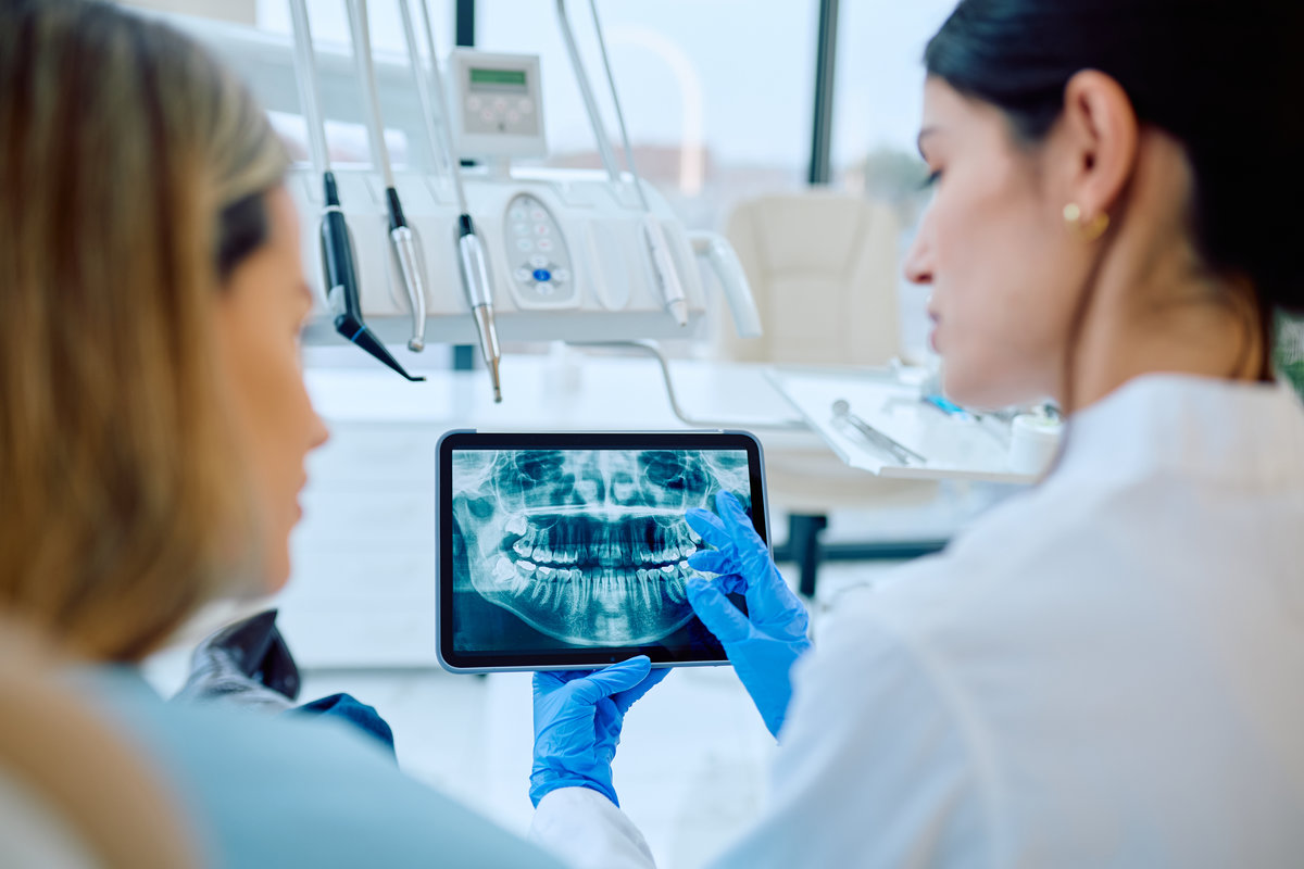Dentist explaining dental x-ray to patient using tablet