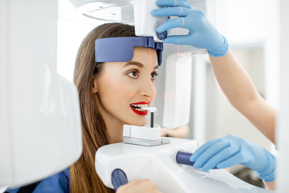 Young woman making panoramic shot of the jaw holding her face at the x-ray machine