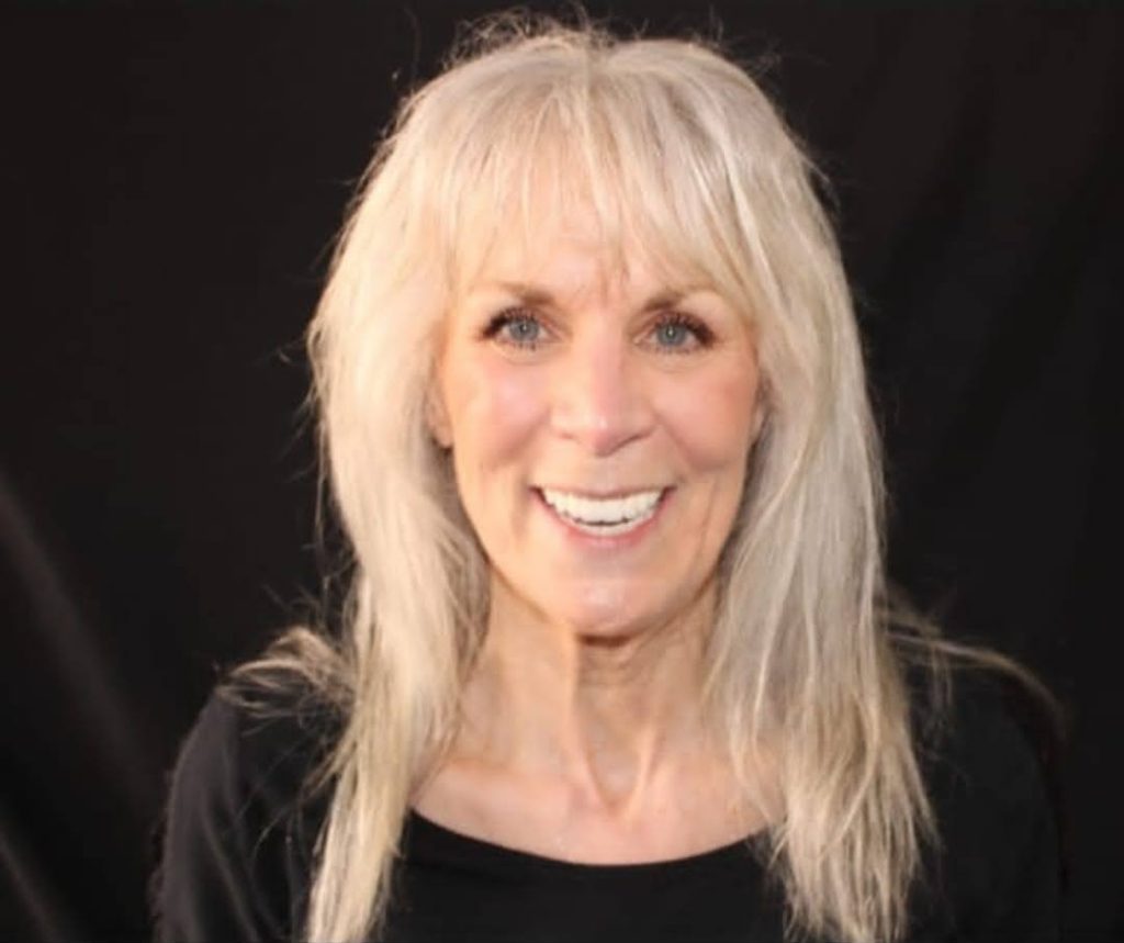 Mature woman with blonde hair smiling, displaying bright white teeth after dental work
