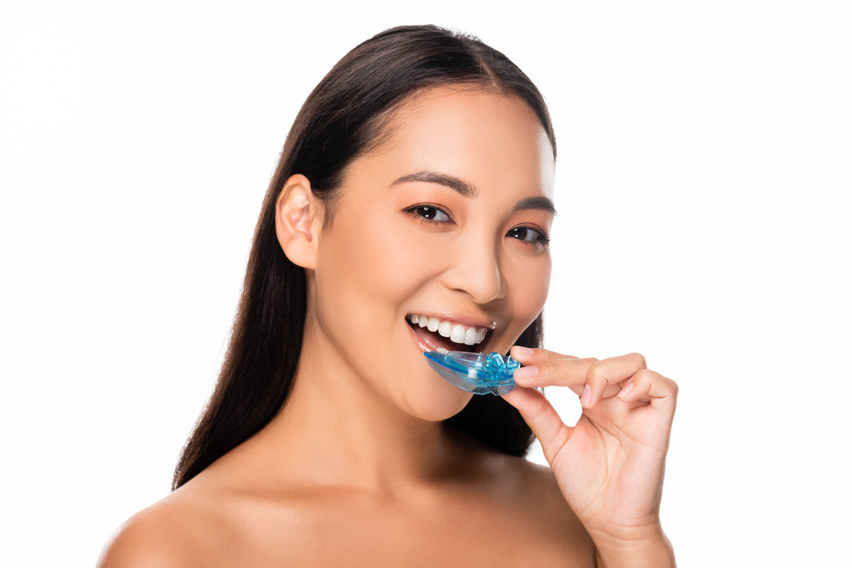 happy naked asian woman holding mouth guard isolated on white