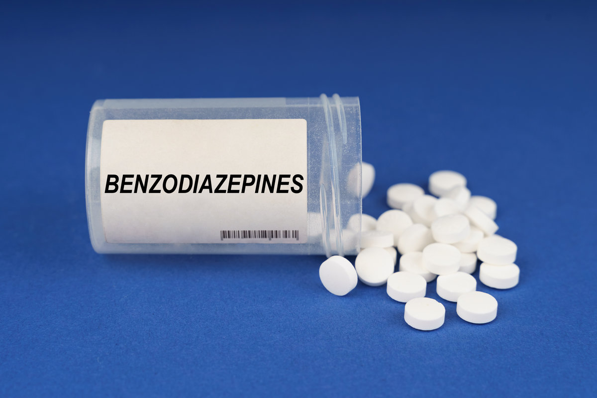 The concept of pharmacology and health. On a blue surface are pills and a dusty jar with the inscription - Benzodiazepines
