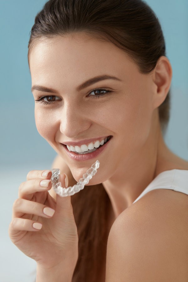 Dental care. Smiling woman using removable clear teeth braces